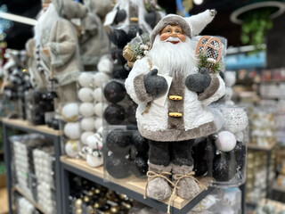 A traditional figure of Santa Claus in a white suit stands in the store against the background of other New Year's toys