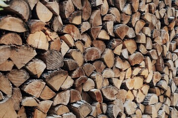 Stacked chopped wood logs in woodpile. Preparation of firewood for the winter. Pile of wood logs in village. Wooden stumps. Alternative Fuel for heat in the house. Industrial concept.
