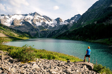 a tourist stands on the shore of the Multin lake with a view of the beautiful mountains