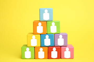 Human resource. Pyramid of colorful cubes with human icons on yellow background