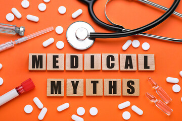 Medical myths. Flat lay composition with wooden squares and medical supplies on dark orange...