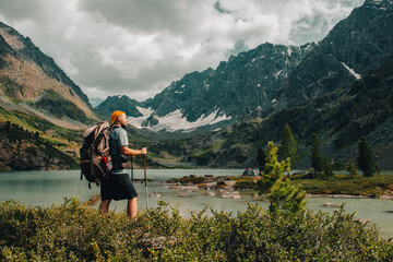 a tourist guy with a backpack looks at the beautiful mountains in Altai