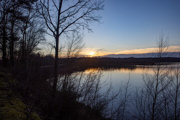 A peaceful sunset reflecting on still water, framed by lush trees, ideal for nature lovers and relaxation