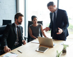 Professional, laptop and business people in meeting, conversation and brainstorming with discussion. Group, coworkers and employees in boardroom, computer and feedback for company website or planning