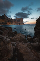 The rock rises above the blue sea at sunset or sunrise