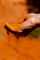 Red sand runs through hand with red sand rocks as background