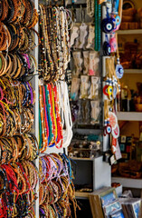 Friendship bracelets, bead necklaces and gift stall. Rows of brightly coloured trinkets for sale. Tourist market.