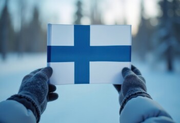 A person displays the Finnish flag, surrounded by a serene winter landscape, highlighting national identity amidst snowy surroundings