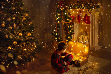 Naklejka premium Christmas Room background with Fireplace and Xmas Tree Lights. Little Child opening Christmas Presents in Vintage Suitcase. Xmas cozy Home Decorations