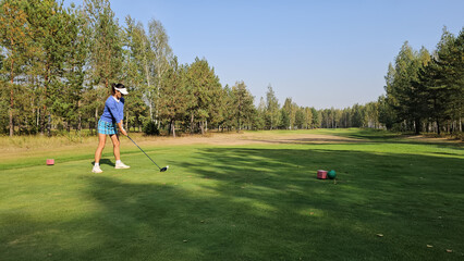 Fototapeta premium Golfer preparing to tee off on a sunny afternoon at a scenic woodland golf course concept