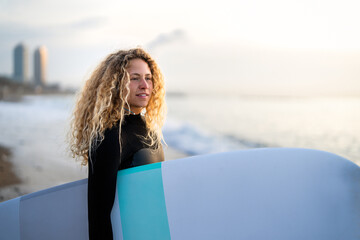 Portrait of happy young woman, girl with surfboard, smiling and enjoying holiday and water sports