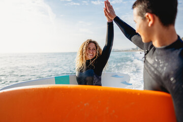 Two happy young surfers with surfboard prepares to hit the waves at sunset. Sports active vacation