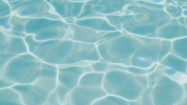 Close-up of sun-dappled blue water, where light creates dynamic wave patterns and reflections on the surface. Water backdrop. Summer concept