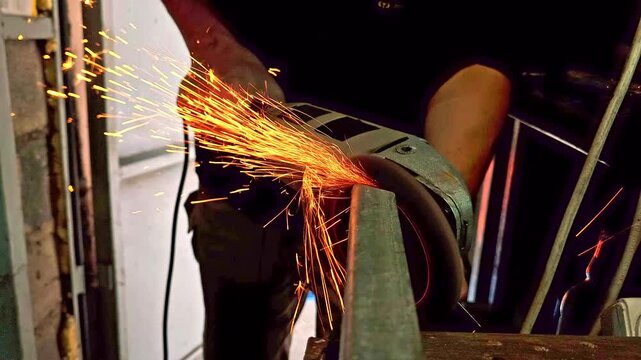 angle grinder with flap disc is polishing end of steel channel after cutting in a garage.