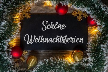 Weihnachtsgrüße: Schild mit der Aufschrift SCHÖNE WEIHNACHTSFERIEN mit weihnachtlicher Dekoration