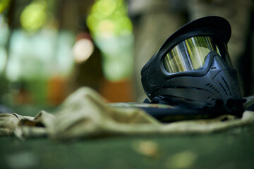 Paintball protective mask, Paintball battle, Game equipment. Black paintball mask, on the artificial playing field, Before the game. Paintball mask