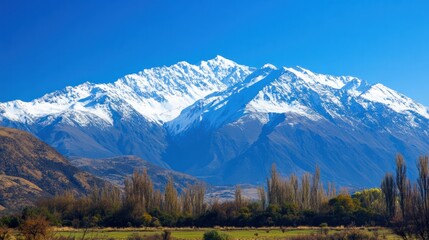 Fototapeta premium Snow-capped mountains under a clear blue sky, perfect for winter travel background themes