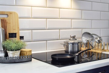 The frying pan and saucepan are on a modern induction hob. The area around the hob is illuminated...