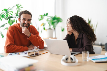 Two young adults share a smile across the table during a study session, bringing a sense of warmth and camaraderie to their learning environment.