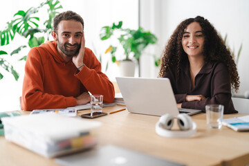 Two young adults share a smile across the table during a study session, bringing a sense of warmth and camaraderie to their learning environment.
