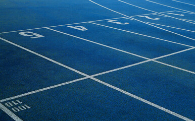 Blue running tracks with white lane markings and numbered start lines.