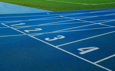 Blue running tracks with white lane markings and numbered start lines.