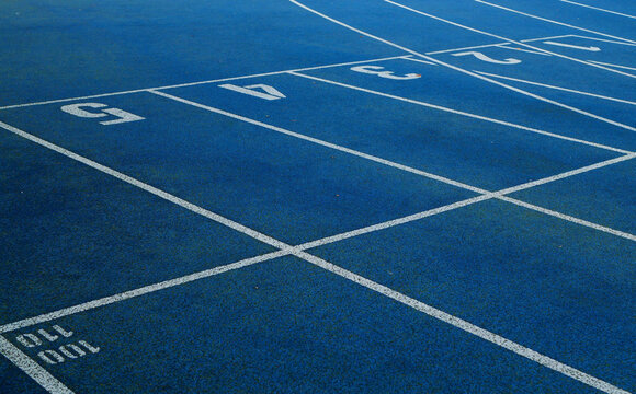 Blue running tracks with white lane markings and numbered start lines.