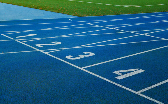 Blue running tracks with white lane markings and numbered start lines.