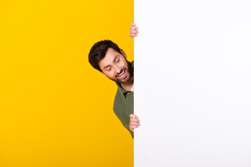 Photo of nice young man look empty space ad wear shirt isolated on yellow color background © deagreez