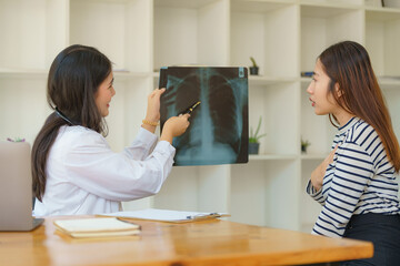 Asian female doctor explaining lung x-ray film of a female patient at the hospital.