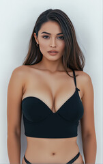 Fototapeta premium Portrait of attractive young slim woman with fit body in black bikini on plain background. Advertising fashion photo shoot, concept.