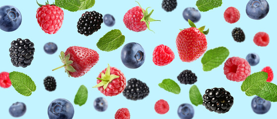 Mix of fresh berries in air on light blue background