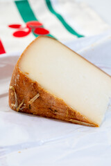 Piece of tasty Basque Brebis Fume smoked sheep cheese produced in south-western France, Northern Basque Country and towel with Basque symbol and colours