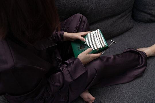 Girl playing kalimba at home with close-up on kalimba keys. Kalimba, the finger harp or mbira. traditional African thumb piano. A tuning hammer lies nearby, ready to adjust the instrument  