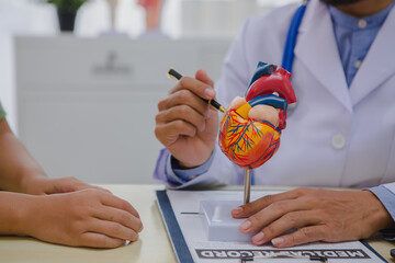 A male doctor is diagnosing a patient with heart disease and explains the symptoms of heart disease...