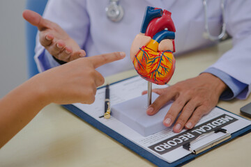 A male doctor is diagnosing a patient with heart disease and explains the symptoms of heart disease...