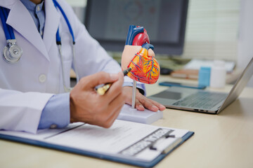A male doctor is diagnosing a patient with heart disease and explains the symptoms of heart disease...