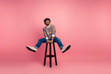 Full body photo of nice young man sit stool look empty space ad isolated on pink color background