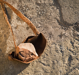 An antique leather sling lies on the ground