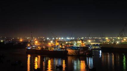 aerial view shipyard dry dock maintenance and repair container ship transport and oil ships in sea, business and industry service at night over lighting photograph from drone,