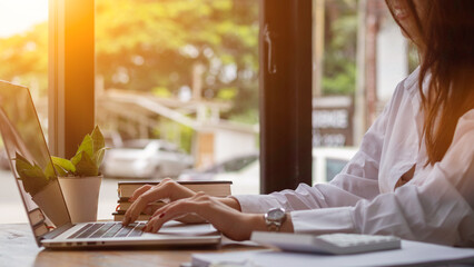 young businesswoman is reviewing results of corporate network via laptops and the Internet in order...