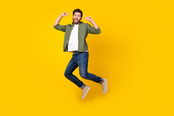 Full length portrait of nice young man jump show v-sign wear shirt isolated on yellow color background