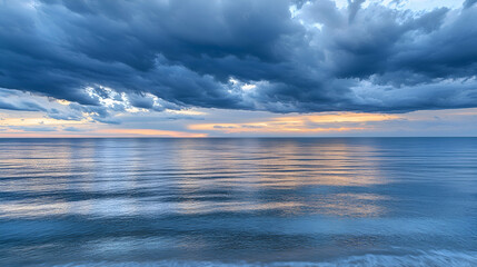 Obraz premium Dramatic stormy sky over a calm sea at sunset.