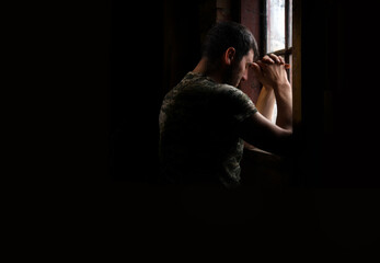 Sad soldier praying at the window