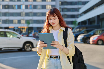 Young female college student using digital tablet outdoor