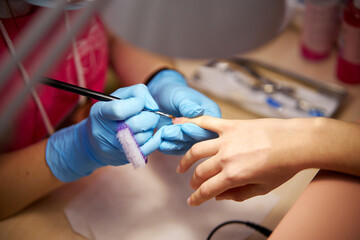 Women's manicure. Female hand undergoing a manicure procedure. The master does a women's manicure. A manicurist files a women's nails in a salon. Hygiene and hand care for woman. manicure design.