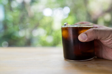 Someone is holding a mug of cool black coffee before drinking in home