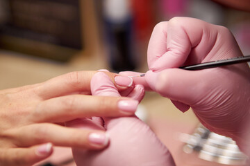 Women's manicure. Female hand undergoing a manicure procedure. The master does a women's manicure. A manicurist files a women's nails in a salon. Hygiene and hand care for woman. manicure design.