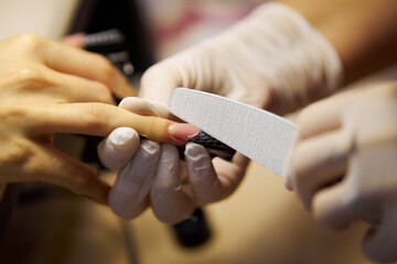 Women's manicure. Female hand undergoing a manicure procedure. The master does a women's manicure. A manicurist files a women's nails in a salon. Hygiene and hand care for woman. manicure design.