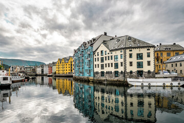 Alesund canal with colorful buildings reflected in water in cloudy day. Norway